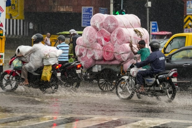 Commuters struggle to move forward on a waterlogged road as heavy rain causes inconvenience and slows down movement for vehicles and pedestrians alike. (Image: ANI)