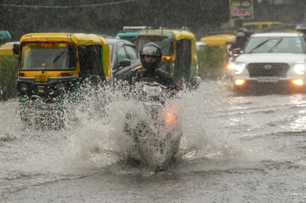 People wade through rainwater on a flooded street, braving difficult conditions as heavy showers drench the area and create traffic snarls. (Source: ANI)