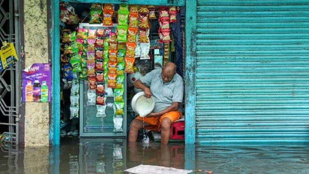 A shopkeeper spills dairy products after rainwater entered his shop. (PTI)
