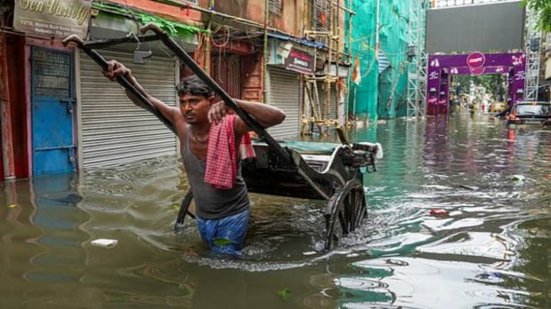 A man pulls a hand rickshaw through a waterlogged area after the overnight rain. (PTI)
