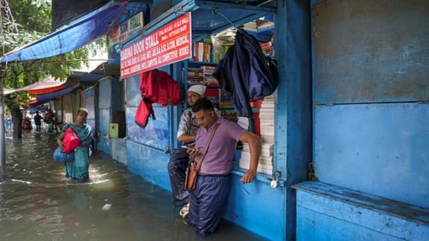 People stand near a bookstore as College Street gets waterlogged due to the rains. (PTI)