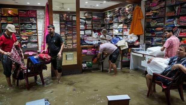 Shopkeepers place goods on raised platforms after water entered their shops amid Durga Puja preparations. (PTI)