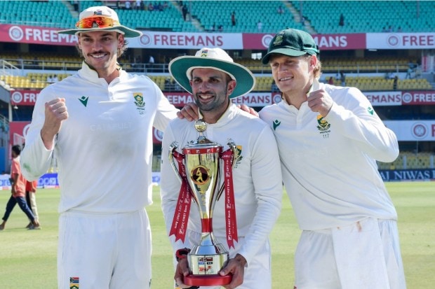 South Africa's Keshav Maharaj (centre) with teammates poses with the trophy after team wins the second Test cricket match between India and South Africa. (Image: PTI)