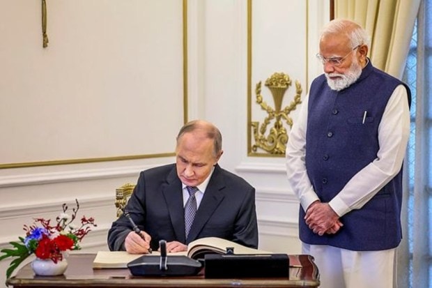Prime Minister Narendra Modi looks on as Russian President Vladimir Putin signs a visitor's book at Hyderabad House, in New Delhi. (Image Source: PTI)