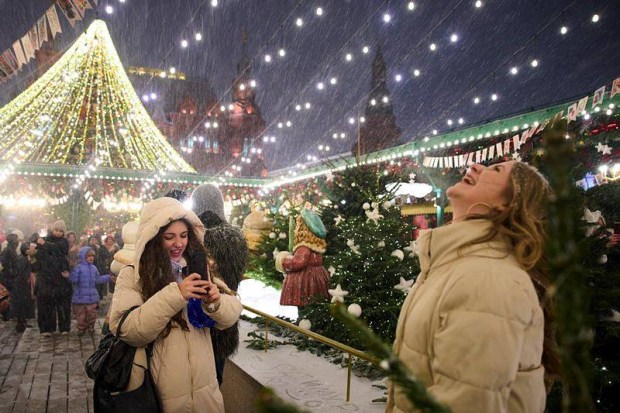 A woman taking a picture of another under snowfall at the Christmas fair in Moscow. (Photo source: AP)