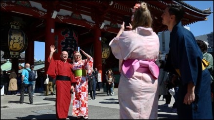 Foreign tourists wearing Japanese traditional kimono clothes pose for a photograph near Sensoji temple at Asakusa district, a popular sightseeing spot in Tokyo (Image source: Reuters)