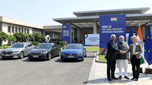 Indian PM Narendra Modi shakes hands with EU leaders António Costa and Ursula von der Leyen next to a lineup of Mercedes-Benz, BMW, and Volkswagen luxury cars at an India-EU FTA summit.