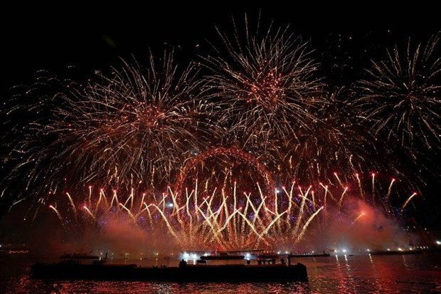 Fireworks arc over bridges and buildings along the Thames, creating a bright background for London’s midnight countdown. (Photo source: AP).