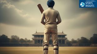 A tall Indian prince wearing a blue turban and vintage white cricket flannels, standing alone on a cricket pitch with a bat in hand.
