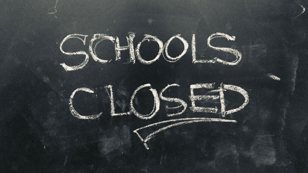 A foggy morning view of a closed school gate in Northern India with a notice board mentioning the extension of winter vacation until January 15.