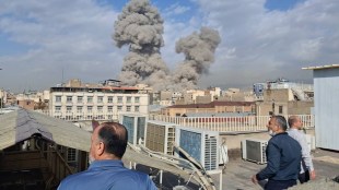 People watch as smoke rises on the skyline after an explosion in Tehran (Photo: AP)
