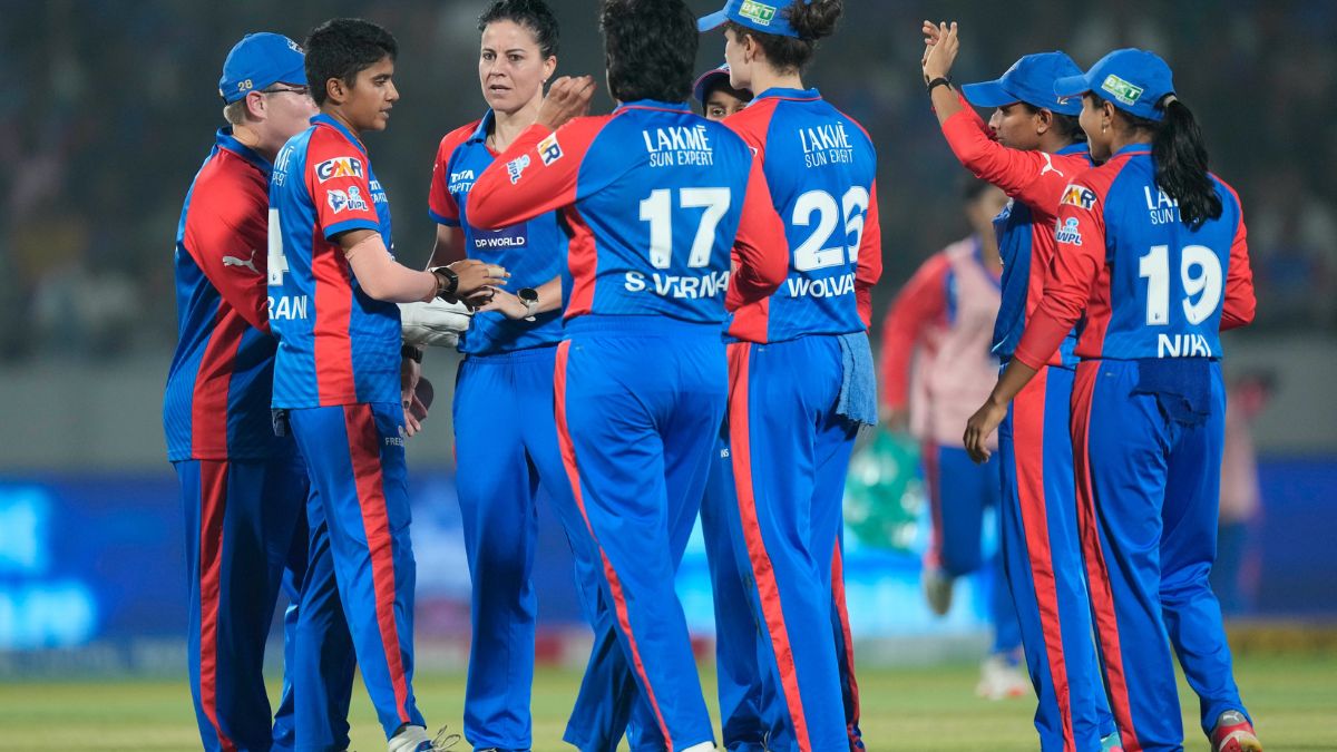 Delhi Capitals players celebrating the fall of a wicket during a WPL 2026 match.