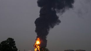 Fire and plumes of smoke rises after a drone struck a fuel tank forcing the temporary suspension of flights. near Dubai International Airport on March 16 (Photo: AP)