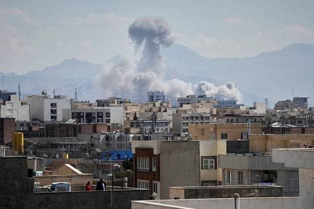 On Sunday, March 1, 2026, a cloud of smoke rises from a strike in Tehran, Iran, and people watch from a rooftop.(Photo source: AP)