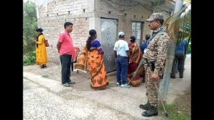 A security official stands guard as people wait in a queue to cast votes during the re-election to the Falta assembly seat in South 24 Parganas district.