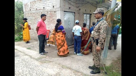 A security official stands guard as people wait in a queue to cast votes during the re-election to the Falta assembly seat in South 24 Parganas district.